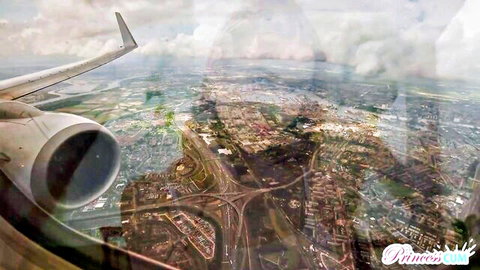 Airplane wing and engine over cloudy cityscape view from window