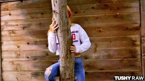 Anastasia Knight seductively hugging tree in white hoodie and ripped jeans