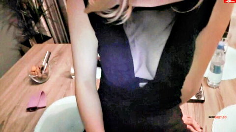 Blonde mature babe in low-cut black dress showing deep cleavage over dinner table