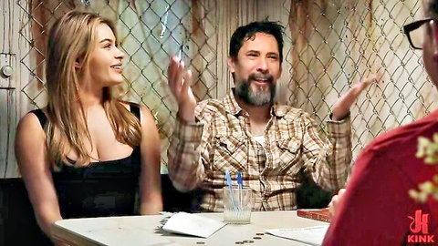 Blonde in tight black top smiles gesturing with bearded guy in plaid shirt at Kink table interview