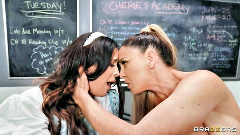 Busty blonde and brunette women kissing intimately in classroom threesome