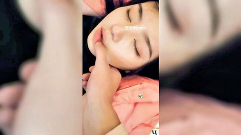 Seductive Korean amateur girl with closed eyes, touching lips in pink jacket