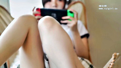 Cute Asian teen gamer girl spreading legs in plaid skirt playing Nintendo Switch