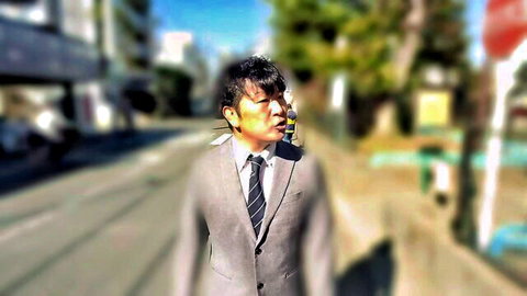 Asian man in gray suit walking on sunny urban street
