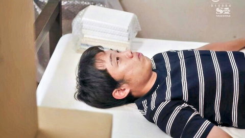 Handsome Japanese guy lying relaxed on bed in striped shirt