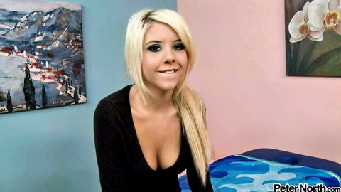Smiling blonde babe with huge tits in low-cut black top showing deep cleavage