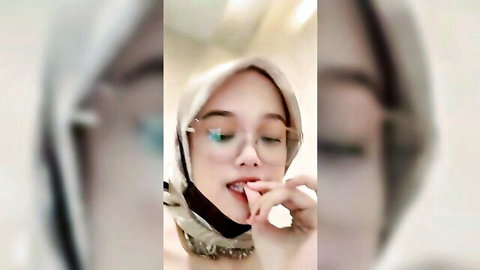Malaysian hijab girl in glasses seductively licks and sucks her finger teasing blowjob