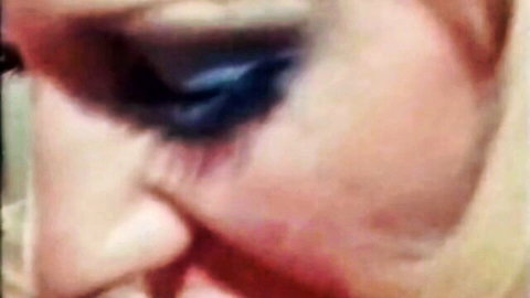 Close-up of blonde retro porn star with heavy blue eyeshadow, intense gaze from Tabu Film classic