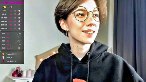 Cute glasses-wearing girl smiles seductively on live webcam stream in hoodie