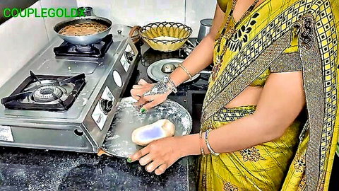 Indian wife in yellow saree making chapati dough on kitchen stove