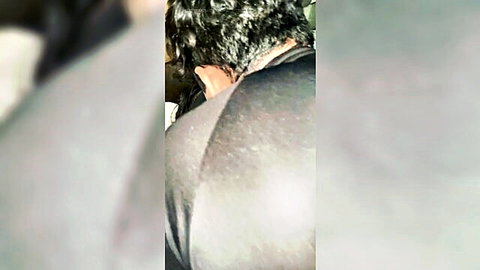 Blurry closeup of man's wet black hair and muscular shoulders in tight dark shirt from behind