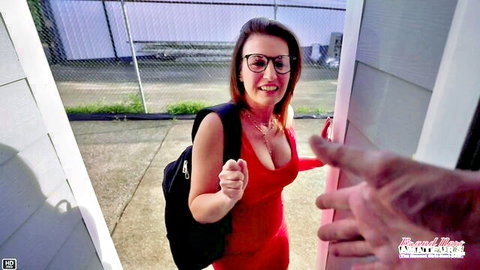 Busty brunette MILF in tight red dress smiles thumbs up with man's hand on her shoulder at amateur audition door