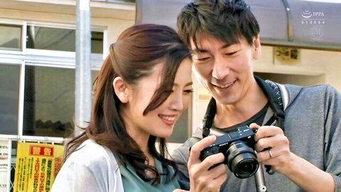 Smiling Japanese beauty poses closely with man holding camera outdoors