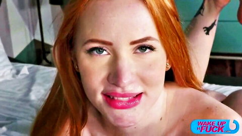 Smiling nude redhead with medium tits and glossy lips lying on bed