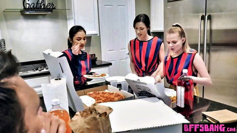 Three sexy referees in tight striped uniforms opening pizza boxes in kitchen with watching guy