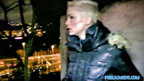 Short-haired blonde babe in shiny puffy jacket looking seductive outdoors at night