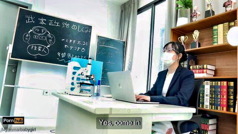 Asian teacher in glasses mask and suit types on laptop in classroom saying yes come in