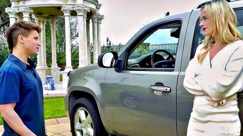 Lindsey Lakes in white dress flirts with young man by silver SUV outdoors
