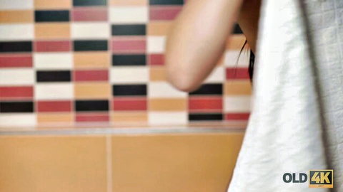 Woman wrapped in white towel exposing shoulder in colorful tiled bathroom