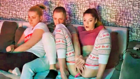Two blondes in reindeer pajamas tease boyfriend's crotch on couch in amateur threesome