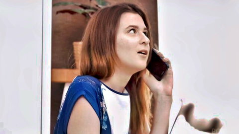 Cute redhead teen girl talking on phone with surprised expression in blue top