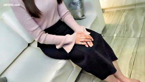Asian woman in pink bell-sleeve sweater and black skirt sitting barefoot