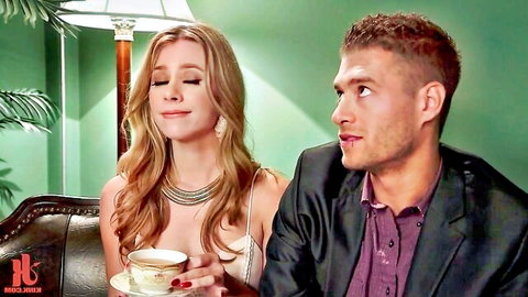 Blonde girlfriend in low-cut dress sips tea seductively with boyfriend in suit