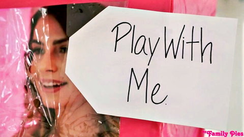 Smiling brunette in pink plastic wrap with 'Play With Me' tag, Barbie parody