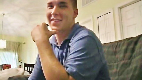 Muscular white guy in blue polo shirt smiling on couch, teasing vibe