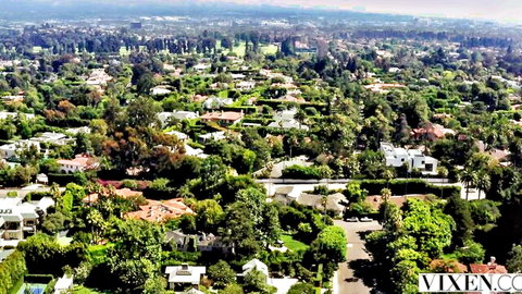 Aerial drone view of lush green suburban neighborhood with luxury houses trees and distant hills