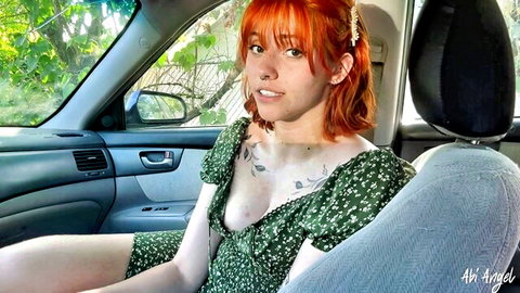 Redhead woman in green floral dress showing cleavage in car