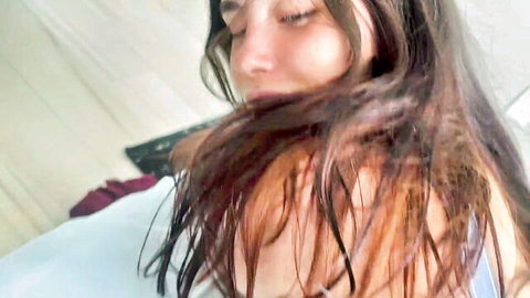 Closeup of ecstatic brunette teen with eyes closed moaning in pleasure on bed