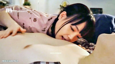 Japanese beauty in pink top passionately kissing shirtless man on bed in sensual taboo embrace