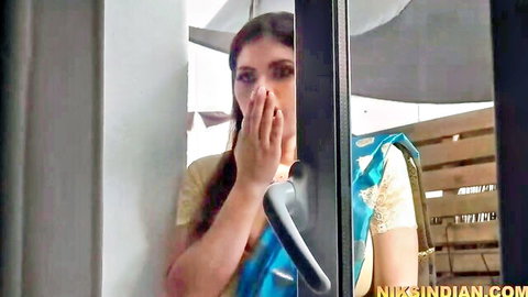 Sexy Indian brunette in blue saree peeking through door with hand on mouth