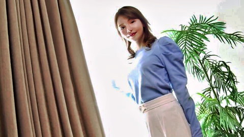 Cute East Asian girl in blue puffy sleeve blouse and beige pants smiling seductively indoors