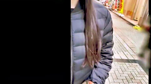 Busty Asian woman in black puffer jacket showing H cup cleavage on urban street