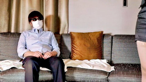 Masked Japanese man sits while woman in mini skirt stands seductively nearby