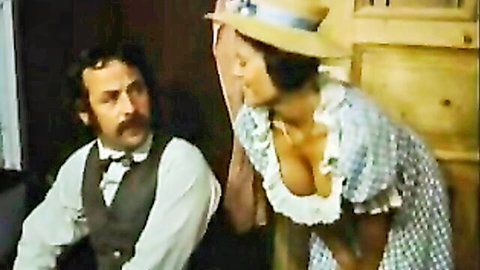 Busty vintage woman in checkered dress and straw hat flashes deep cleavage kissing bearded man in vest
