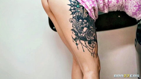 Maddy O'Reilly bends over in pink dress revealing thigh tattoo