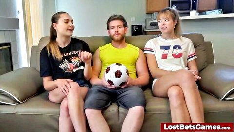 Brunette and blonde petite teens in tiny shorts with buff guy holding soccer ball on couch