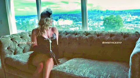Blonde beauty in sheer black lingerie teases massive tits cleavage on velvet couch overlooking city skyline
