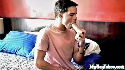 Twink boy sucking thick white dildo in mouth on bed wearing pink shirt