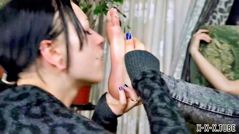 Slim Asian woman with black hair lifts foot with blue toenails for worship