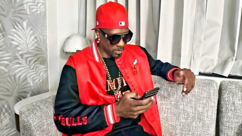Mature Black man in Chicago Bulls jacket and cap, checking phone in JaylaP Sweet Tooth For Chocolate