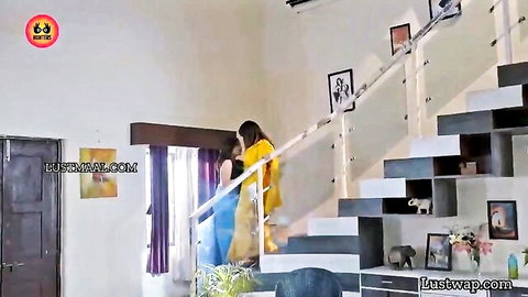 Two Indian women in colorful sarees share intimate embrace on stairs