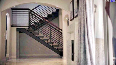 Modern luxury home interior featuring black metal staircase under arched doorway with soft lighting