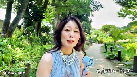 Elegant Japanese wife in blue top and pearls, smiling in lush garden