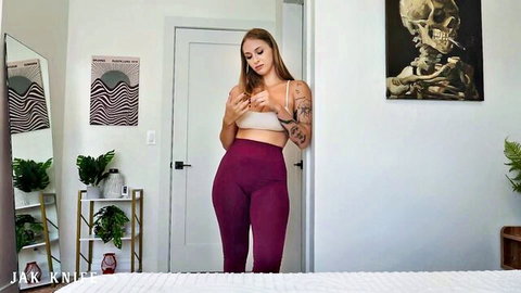 Angel Youngs in tight purple leggings and white bralette, curvy tattooed tease