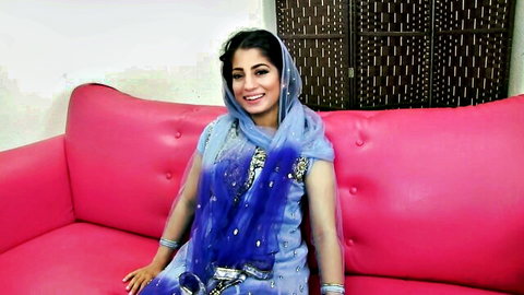 Nadia Ali in blue traditional Pakistani attire, smiling on couch