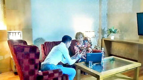 Blonde woman and Asian man in intimate laptop consultation scene